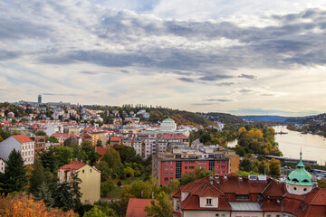 Fototapeta premium view of Prague in autumn: houses with red roofs, old and new buildings and the river
