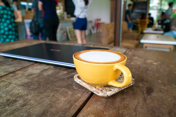 Hot latte art coffee with laptop on wooden table