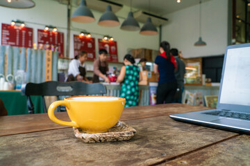 Hot latte art coffee with laptop on wooden table
