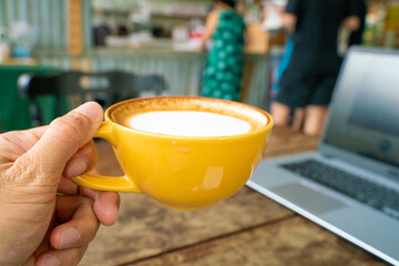 Hot latte art coffee with laptop on wooden table