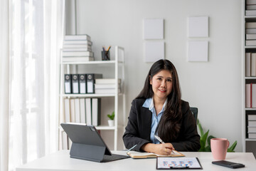 A woman is sitting at a desk with a laptop and a notebook