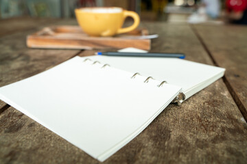 Hot latte coffee cup on wood table with blank notebook