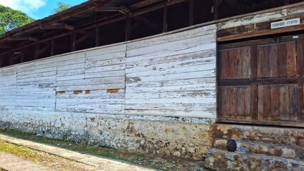Fototapeta premium A weathered wooden building with a large wooden door and whitewashed walls