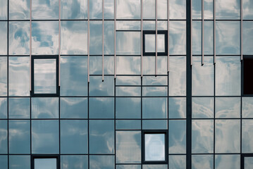 Fototapeta premium empty glass windows of a modern building with a reflection of the sky in the glass