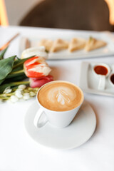 delicious dish of pancakes with various sauces, accompanied by a fragrant cup of coffee in a white mug, on a wooden table in a cozy, charming restaurant