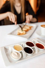 handsome girll is eating delicious dish of pancakes with various sauces, accompanied by a fragrant cup of coffee in a white mug, on a wooden table in a cozy, charming restaurant