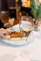 cute girl is eating a delicious dish with juicy salmon, fresh vegetables, avocado, and fragrant herbs, served on a beautiful white plate on a wooden table in a cozy, charming restaurant