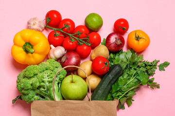 Delivery of vegetarian products. Paper bag with different vegetables and fruits on pink background, top view