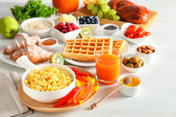 Tasty breakfast. Scrambled eggs in bowl, cut bell pepper, honey and other food on light table