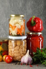 Different pickled products in jars on wooden table