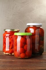 Different pickled vegetables in jars on wooden table