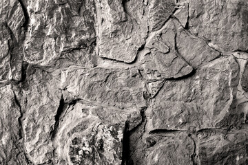 Rough Stone Wall in Black and White. A detailed close-up of a rough stone wall captured in black and white. Ideal for backgrounds, architectural themes, or monochrome design elements.