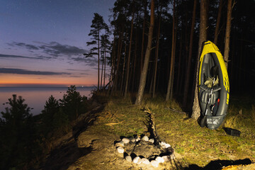 Estonia nature landscape, inflatable boat kayak, paddle and life jacket on the island of Pedassaar. Night photo, starry sky and fire pit.