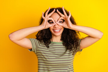 Photo of funky good mood girl with wavy hair dressed striped t-shirt showing binoculars on face...