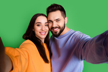 Fototapeta premium Photo of cheerful glad charming couple wear trendy clothes take selfie isolated on green color background