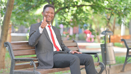 Thumbs Up by African Businessman Sitting on Bench