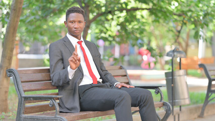 African Businessman Looking at Camera in Denial while Sitting Outdoor
