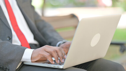 Close up of African Businessman Typing on Laptop in Lap Outdoor