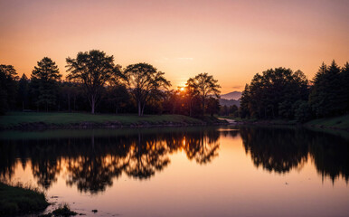 Obraz premium Tranquil Sunset Over Calm Lake Surrounded By Lush Green Trees in Autumn