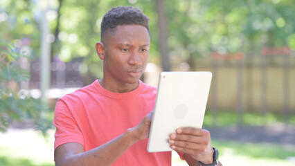 Fototapeta premium Casual African Man Using Tablet while Standing Outdoor