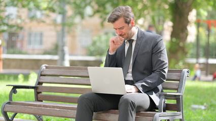 Sick Middle Aged Businessman Coughing while Using Laptop Outdoor