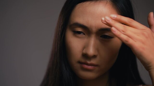 Young Korean woman displeased with her face skin condition, dehydration