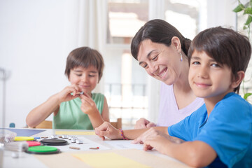 Fototapeta premium Mother and children making handicrafts. On their faces there is a smile reflecting happiness.