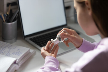 Close up of girl pupil clean disinfect hands at desk with sanitizer protect from corona virus covid-19 pandemic, teenager sanitize take care of hygiene with antibacterial gel, coronavirus concept