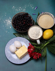 Blueberry pie ingredients on a table. Top view photo of freshly cropped berries, brown sugar, flour, lemon, butter and eggs. Comfort food concept. 