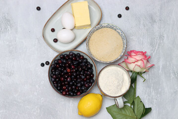 Ingredients for baking pie: flour, eggs, sugar, lemon, blueberries. Light background, top view, copy space