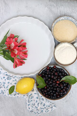 Blueberry pie ingredients on a table. Top view photo of freshly cropped berries, brown sugar, flour, lemon, butter and eggs. Comfort food concept. 