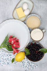 Ingredients for baking pie: flour, eggs, sugar, lemon, blueberries. Light background, top view, copy space