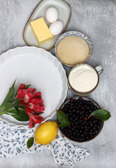 Blueberry pie ingredients on a table. Top view photo of freshly cropped berries, brown sugar, flour, lemon, butter and eggs. Comfort food concept. 