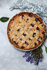Freshly baked blueberry lattice pie on a table. Beautiful golden crust close up photo. Sweet homemade round cake. Light gray background with space for text. 