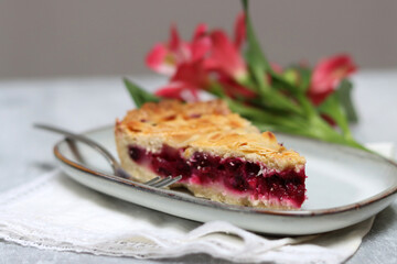 Delicious homemade pie with blueberries and almonds, summer flowers and leaves on light background, top view photo of fresh pastry item 