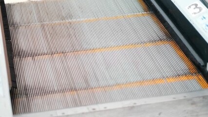 A shallow depth of field top view of a staircase moving up towards the camera, showing the legs of a woman, wearing Black pants and Pink sports shoes, while coming up and goes out of the frame. - Powered by Adobe