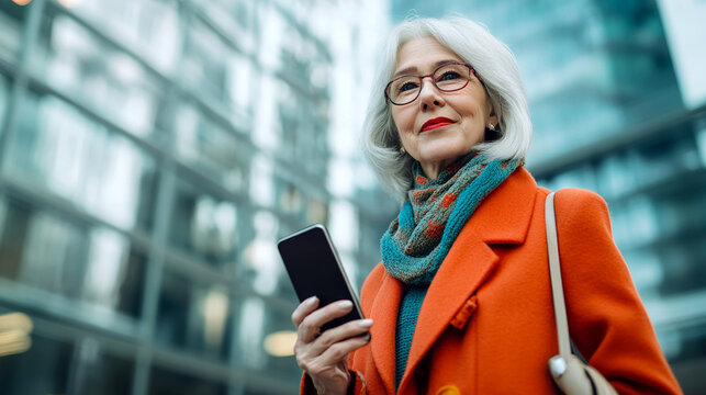Stylish elderly gray-haired woman with smartphone walking along city street demonstrating vitality, fashion and active lifestyle.Confident use of modern gadgets.Generative AI