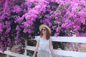 Fototapeta premium mulher com chapéu e óculos de sol em frente a flores roxas