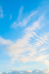 Blue sky sunset landscape with clouds lit by evening sunlight - colorful evening sky view, vertical sunset sky view