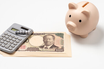 豚の貯金箱と電卓と日本円の新紙幣とアルファベットビーズでmoneyの文字