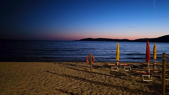 A summer night on the beach in Alghero with the promontory of Capo Caccia on the horizon

