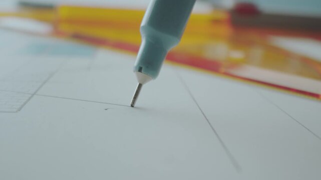 Extreme close-up shot of a professional architect using a pen to draw straight line in the blueprint paper