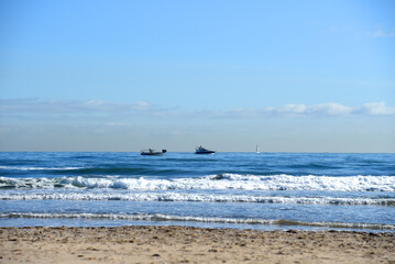 Yacht in the sea. Boats and yachts sail on the sea on the waves. Seascape with yachts in the sea. Beach shore with waves in ocean. Waves in ocean with Waves in sea. Empty sand beach.