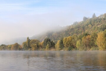 the fog reveals the hill on the river