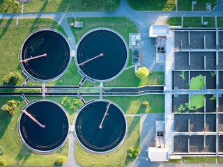 Sustainable water management theme: Aerial, top down  view of industrial clarifiers in wastewater treatment plant in sunset. Elements of urban water treatment technology. 