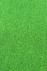 Fototapeta premium Artificial green grass mat, selective focus. Artificial turf, surface made of synthetic fibers. Green grass texture background. Short artificial grass golf surface