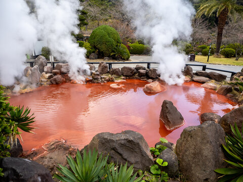 Beppu's Chinoike Jigoku, known as the "Blood Pond Hell." The steamy, red-hued hot spring emits mist from its vibrant, mineral-rich waters, creating an otherworldly, surreal atmosphere. Beppu jigoku.
