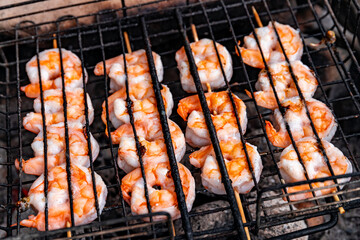 Grilling shrimp over an open fire in the woods.