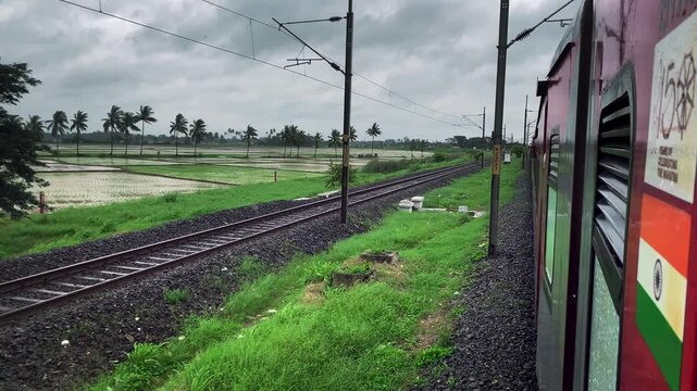Beautiful video of passenger side window pov in an Indian train passing through the lush green paddy fields, flood plains, mountains and jungles during peak Monsoon season in India