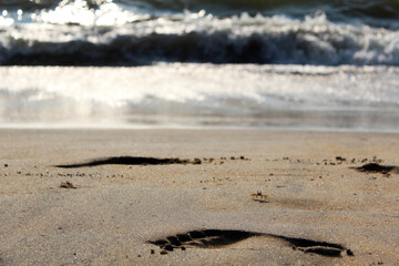 Footprints in the Soft Sandy Beach Accompanied by Ocean Waves in the Background